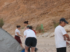 Yael walks across the tent scene: Nehama walks in th eother direction, Molly holds boots, Tani holds poles.