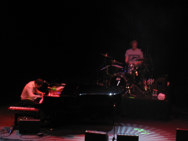 Ben Folds plays piano while his drummer drums