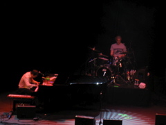 Ben Folds plays piano while his drummer drums